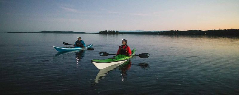 Two kayak guides with headlamps on in the evening preparing for Bioluminescence Kayak Tour